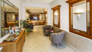 Un hall d’hôtel comprenant un comptoir d’accueil, un espace salon et un téléviseur.