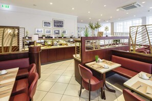 A restaurant with booths and tables, a counter, and framed pictures on the wall. - TOP Hotel Hansa Wiesbaden (Wiesbaden)