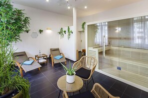 Un espace de détente moderne, avec des meubles en osier, des plantes en pot et une cloison en verre.
