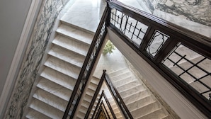 Un magnifique escalier en marbre, avec des marches en marbre et des balustrades noires, menant à l’étage supérieur.