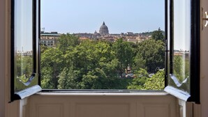 Une vue à travers une fenêtre, offrant une perspective dégagée sur un paysage urbain, avec notamment un imposant bâtiment en forme de dôme et la végétation environnante.