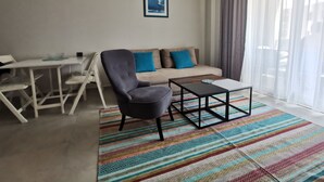 A living room with a sofa, a chair, a coffee table, and a dining table.