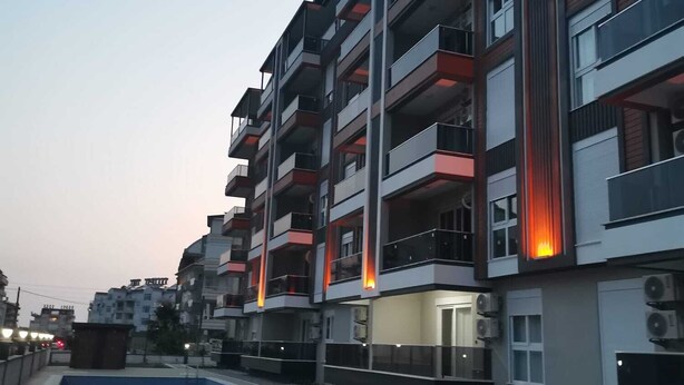 A multi-story residential building with balconies, a swimming pool, and air conditioning units.