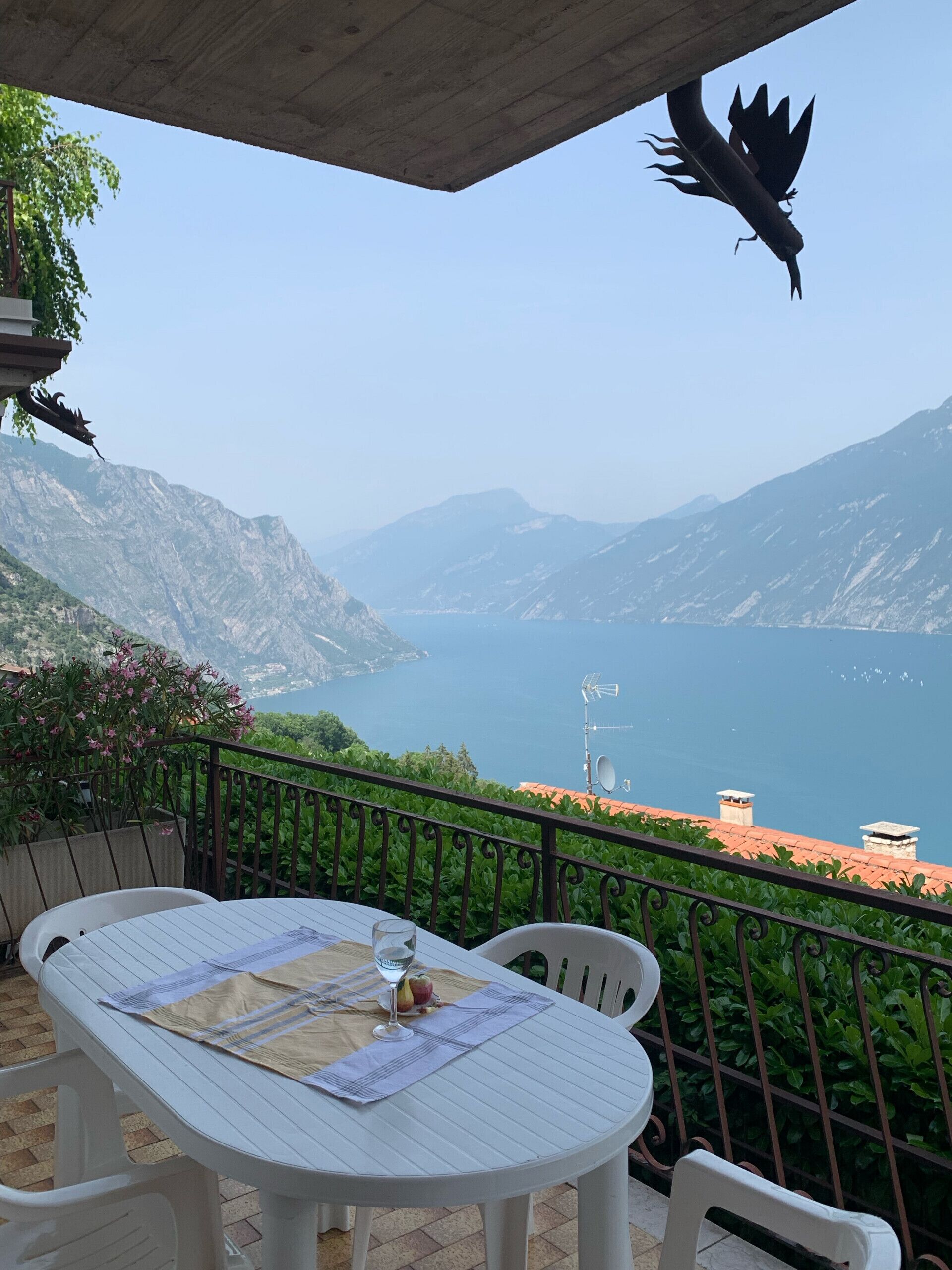 Eine Terrasse mit Tisch für zwei Personen, mit Blick auf eine Berglandschaft und ein Gewässer.