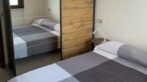 Un dormitorio moderno con una cama grande, una cama más pequeña y un panel de pared de madera.