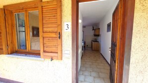 Un couloir menant à une cuisine avec des portes en bois et une enseigne portant le numéro 3.