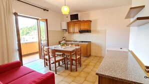 Une cuisine de taille réduite, dotée de meubles de rangement en bois, d’une table à manger et de chaises.
