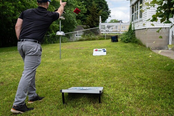 Una persona jugando golf en un jardín trasero con una casa al fondo.