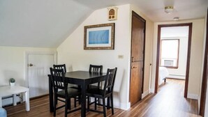 Un comedor con una mesa y sillas de madera, un cuadro en la pared y una puerta que da a otra habitación.