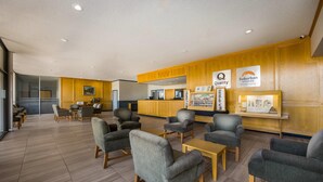 Eine geräumige Lobby mit Holzvertäfelung, bequemen Sitzmöglichkeiten und einem Empfangsbereich mit Hinweisen auf Qualität sowie ein Hotel mit Apartmentwohnungen in einer Vorortlage.