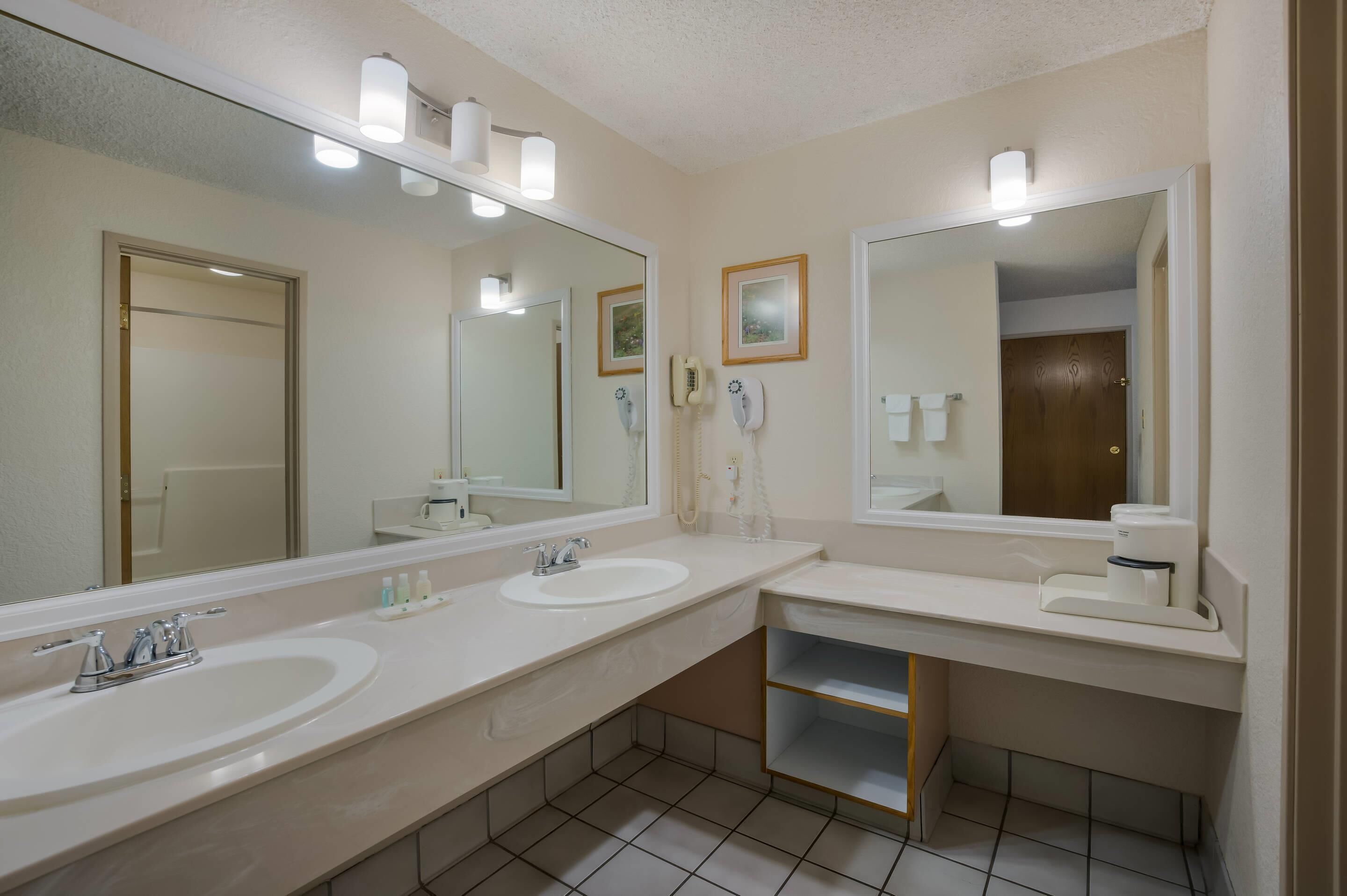 Une salle de bain avec deux lavabos, un miroir et des toilettes.