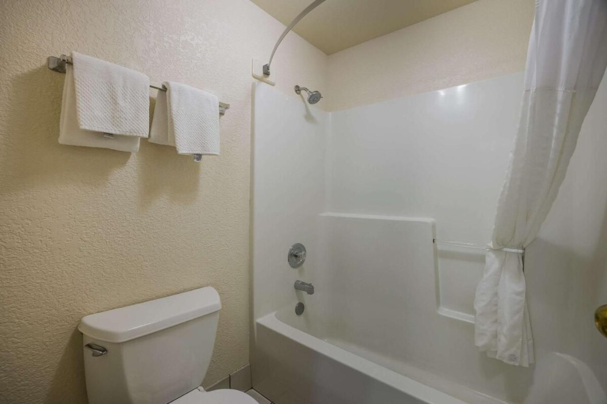 A bathroom with a toilet, a shower with a glass door, and two towels on a rack.