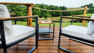 A wooden deck with two white cushioned chairs and a small table with wicker baskets.