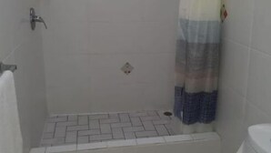 Un baño pequeño con ducha, inodoro y un perchero para toallas.