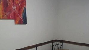 Una habitación de esquina con una mesa y sillas de madera, una pared blanca y dos cuadros abstractos.
