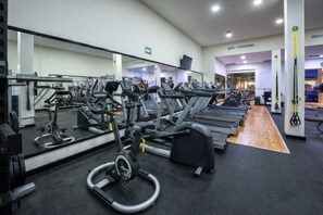 Un gimnasio con cintas de correr, bicicletas estáticas y máquinas de pesas.