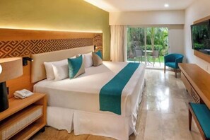 A hotel room with a large bed, a bedside table, a chair, and a view of the outdoors. - Viva Azteca by Wyndham, A Trademark All Inclusive Resort (PLAYA DEL CARMEN)
