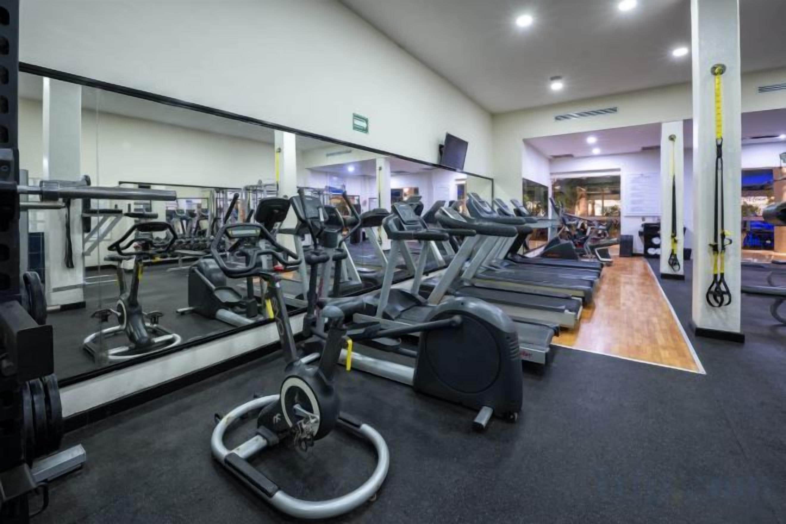 A gym with treadmills, elliptical machines, and weightlifting equipment.