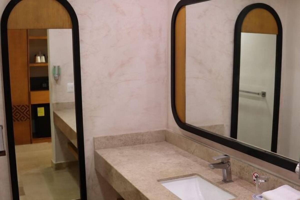 A bathroom with a marble countertop, a sink, a mirror, and a shower area.