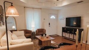 Un salon moderne avec un canapé, des fauteuils, une table basse, un téléviseur et une cheminée décorée de bougies.