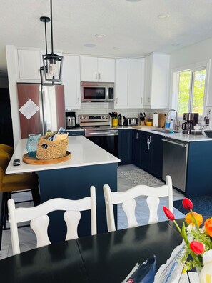 Een moderne keuken met witte kastjes, roestvrijstalen apparatuur en een centraal kookeiland met zitplaatsen.