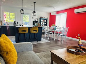 Een moderne keuken met een centraal eiland, barstoelen en een eethoek met witte stoelen.