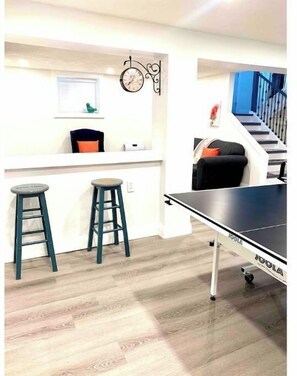 Relax and play in this compact living space, featuring a ping pong table and casual seating area.