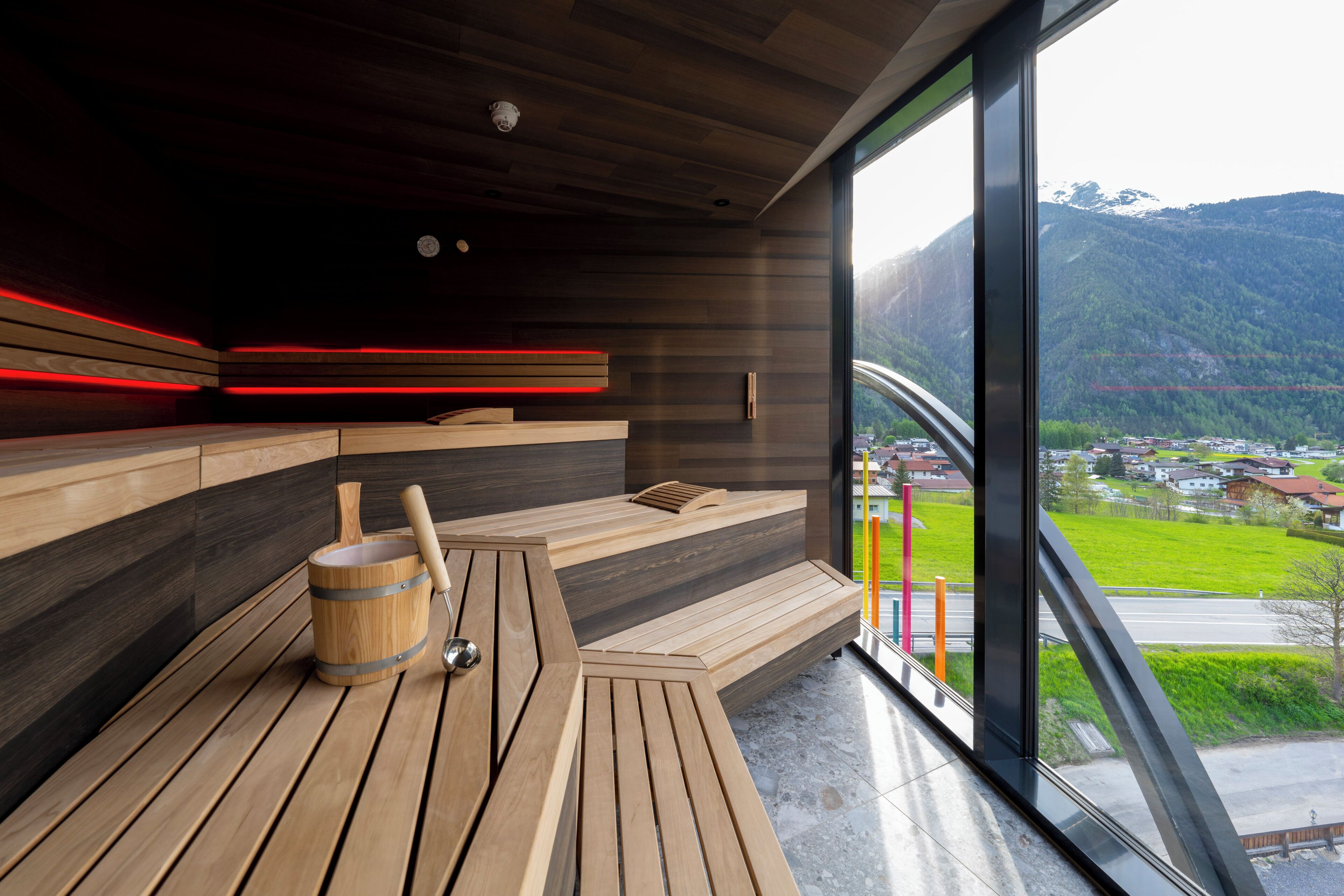 A sauna with wooden benches and a wooden bucket.