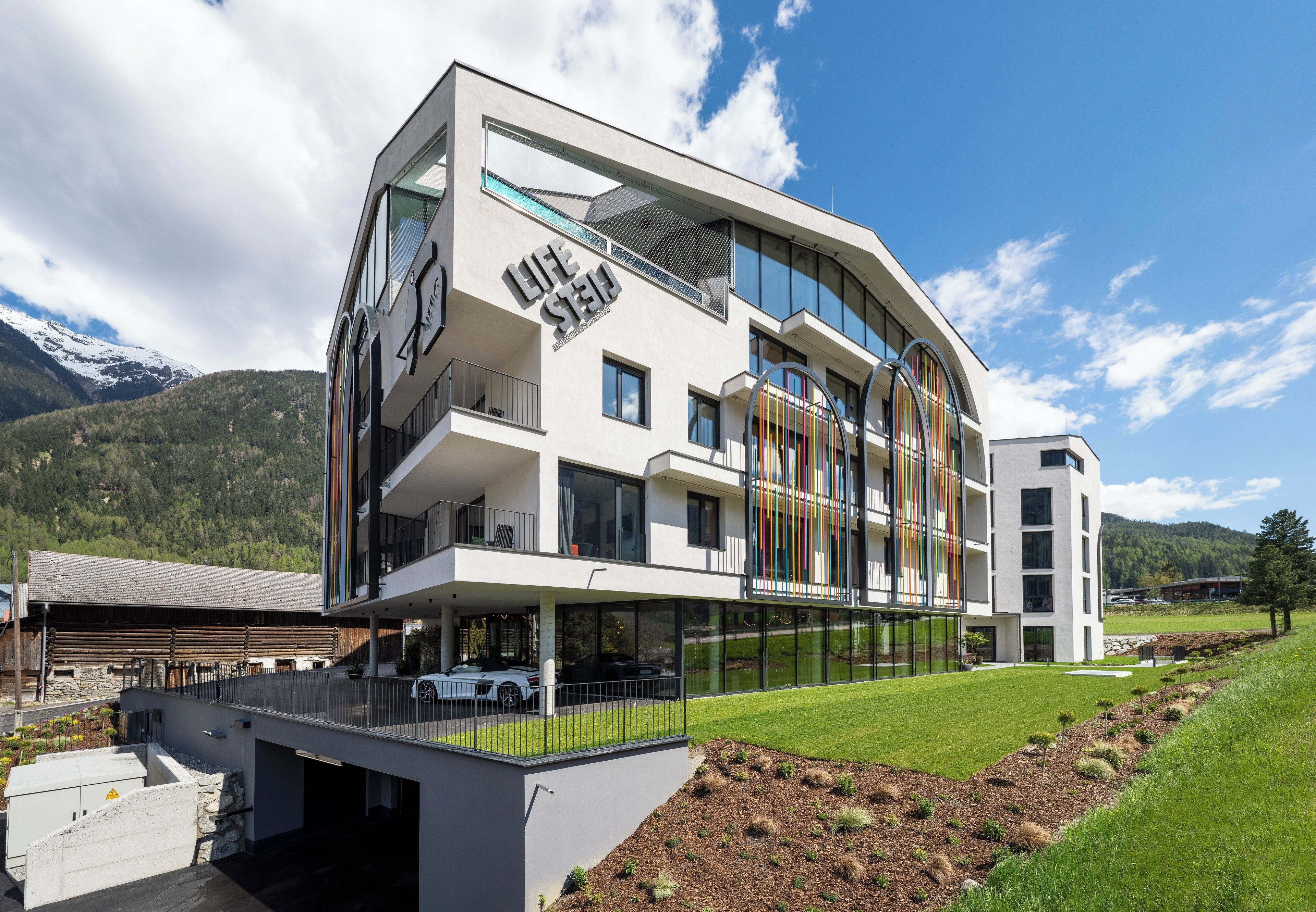 Un hôtel moderne doté d’une façade en verre, de nombreux balcons et offrant une vue sur des montagnes enneigées.