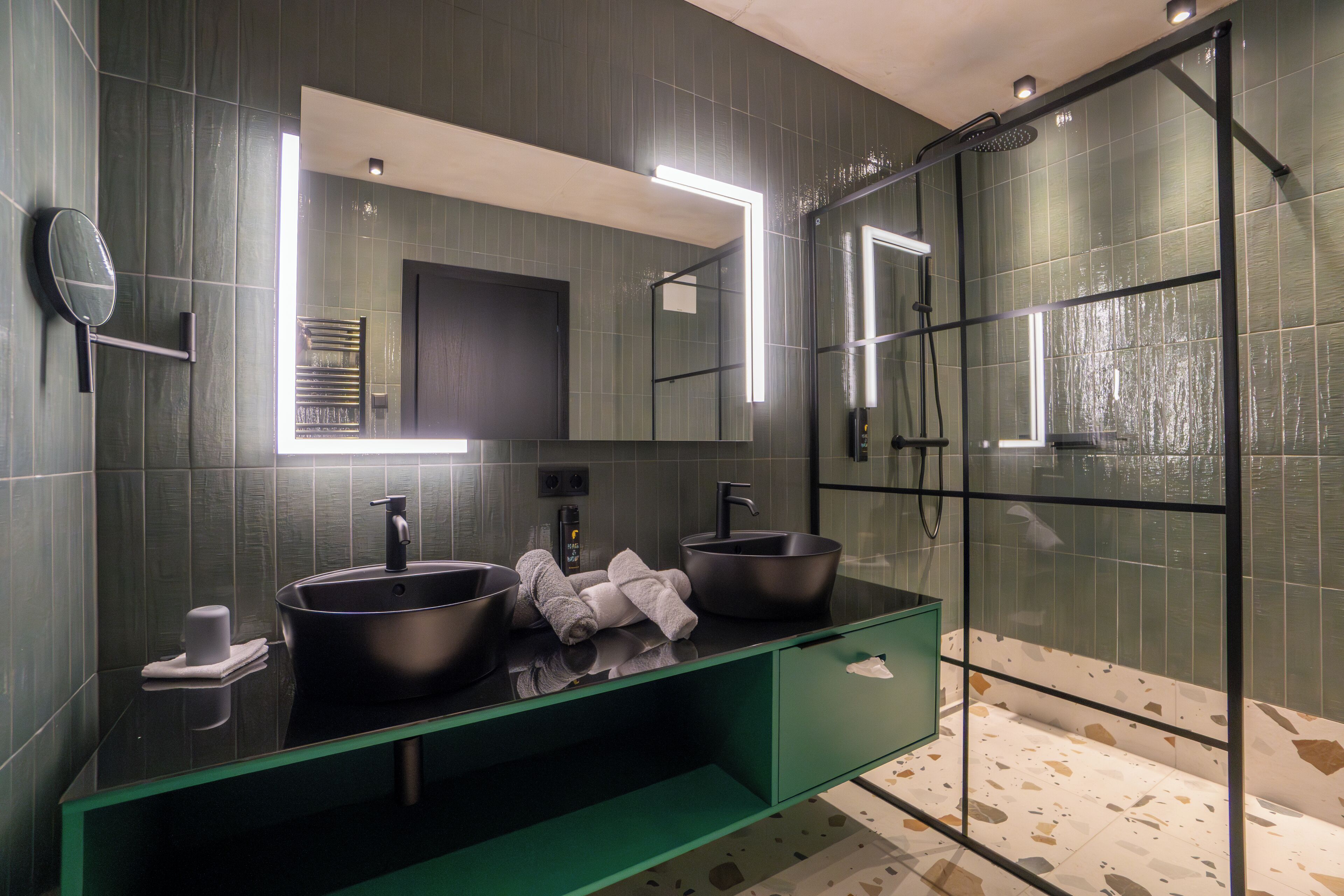 A modern bathroom with two sinks, a large mirror, and a glass shower enclosure.