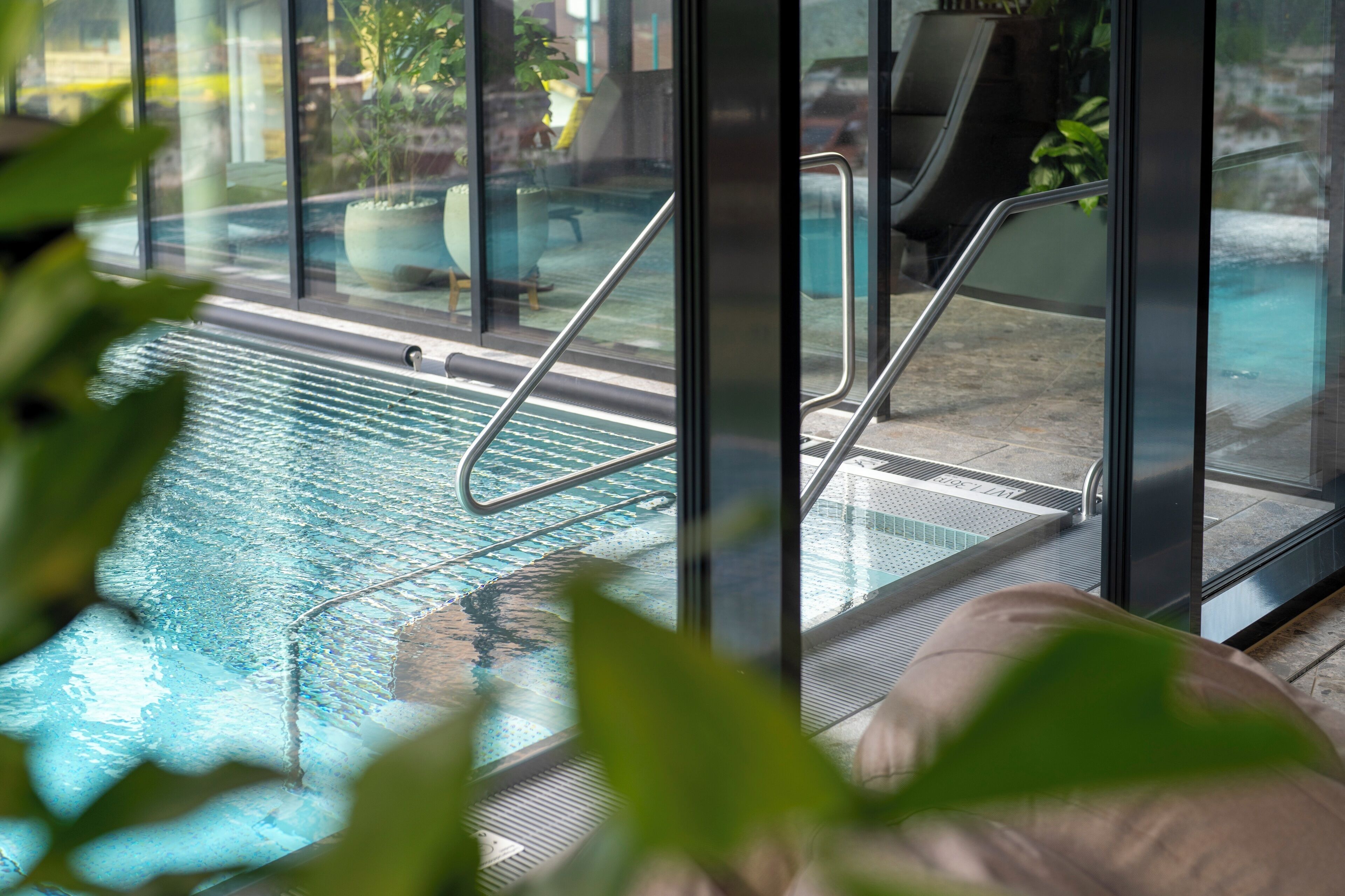 A glass-enclosed indoor pool with metal railings and a view of the surrounding area.