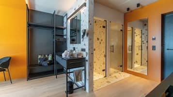 Un baño moderno con ducha de vidrio, lavamanos con artículos de aseo y un perchero para toallas.