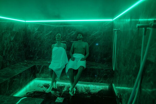 Una habitación con pared de mármol e iluminación verde en el techo.