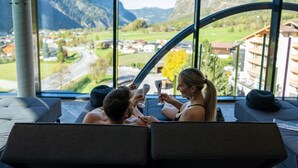 A room with a large window offering a view of a mountainous landscape. - LIFESTEIL Appartementresort (Umhausen)