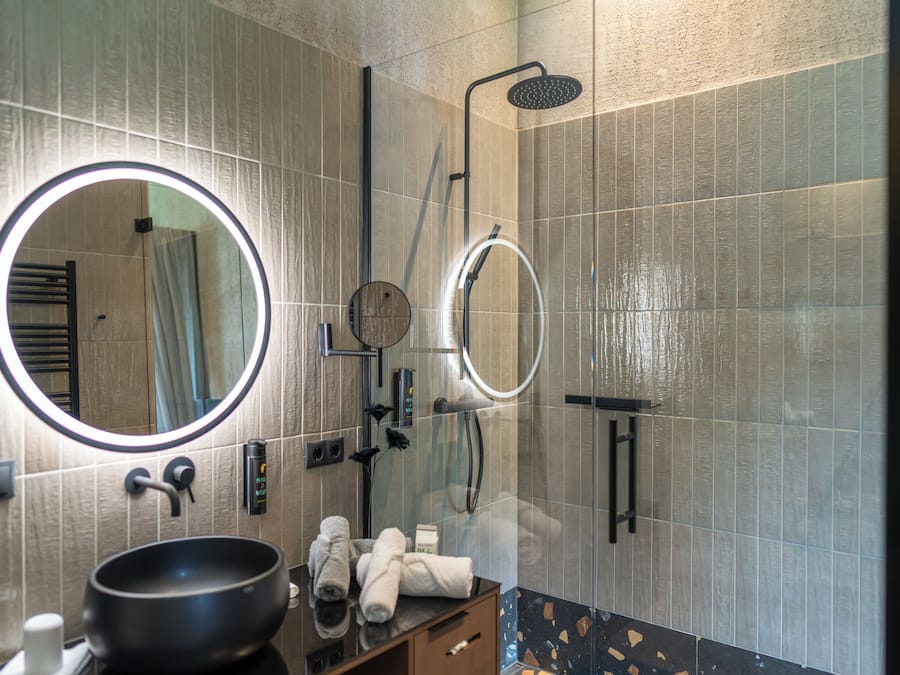 A modern bathroom with a round mirror, a sink, and a shower.