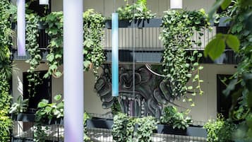 Un edificio con balcones cubiertos de follaje, un mural con diseño de dragón y plantas colgantes.