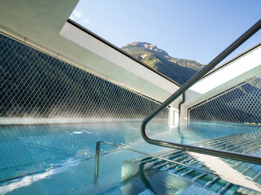 Une piscine intérieure offrant une vue sur les montagnes à travers une paroi de verre.