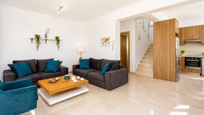 Una sala de estar moderna con un juego de sofá, una mesa de centro y una zona de cocina con una escalera.