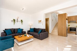 Una sala de estar moderna con un juego de sofá, una mesa de centro y una zona de cocina con una escalera.