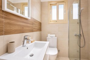 Une salle de bain moderne avec un lavabo, des toilettes et une douche, le tout de couleur blanche.