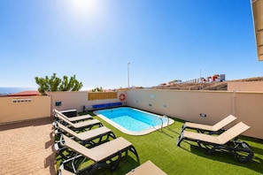 Una piscina sul tetto con lettini, un galleggiante e vista libera sul mare.
