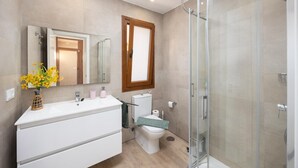 Ein modernes Badezimmer mit einer Duschkabine aus Glas, einem weißen Waschtisch und einem WC mit grünem Sitz.