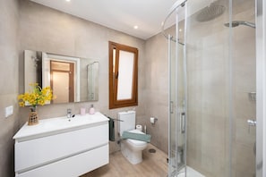 Ein modernes Badezimmer mit einer Duschkabine aus Glas, einem weißen Waschtisch und einem WC mit grünem Sitz.