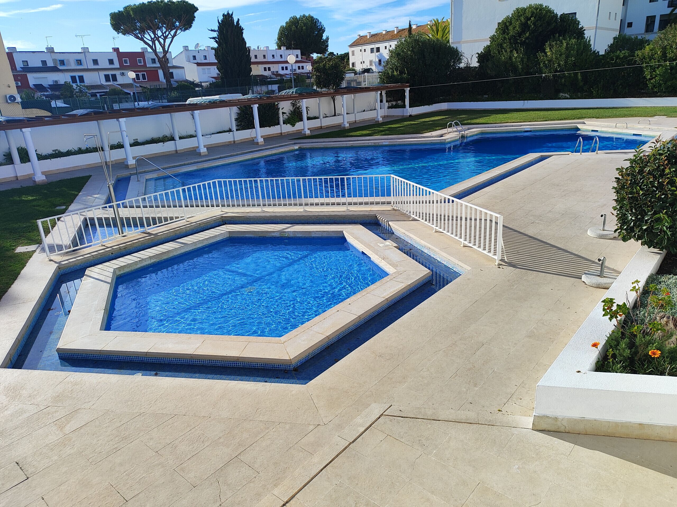 A swimming pool with a white deck and a surrounding fence.