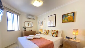 Une chambre d’hôtel comprenant un lit, des tables de chevet, une commode, un miroir et des œuvres d’art accrochées aux murs.
