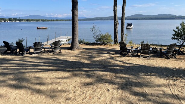 A lakeside seating area with Adirondack chairs and a dock. - Lakefront home on Ossipee Lake with dock and gorgeous views  (Ossipee)
