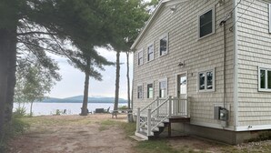 A two-story house with a front porch, a staircase, and a view of a lake. - Lakefront home on Ossipee Lake with dock and gorgeous views  (Ossipee)