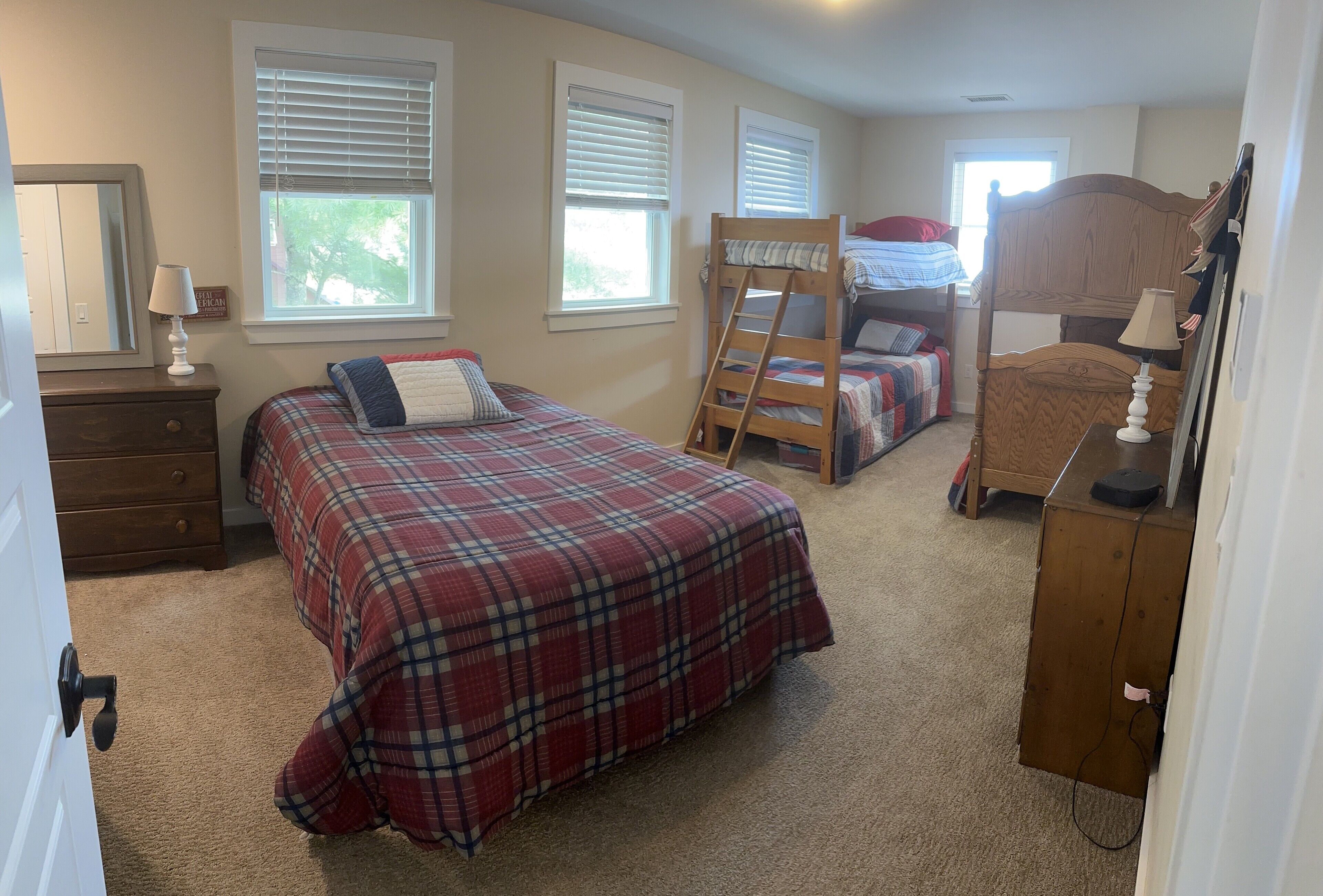 A bedroom with a large bed, a bunk bed, a dresser, and a ladder.