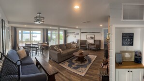 A spacious living room with a large window overlooking a lake, a cozy seating area with a sofa and a coffee table, and a fireplace with a welcome sign. - Lakefront home on Ossipee Lake with dock and gorgeous views  (Ossipee)