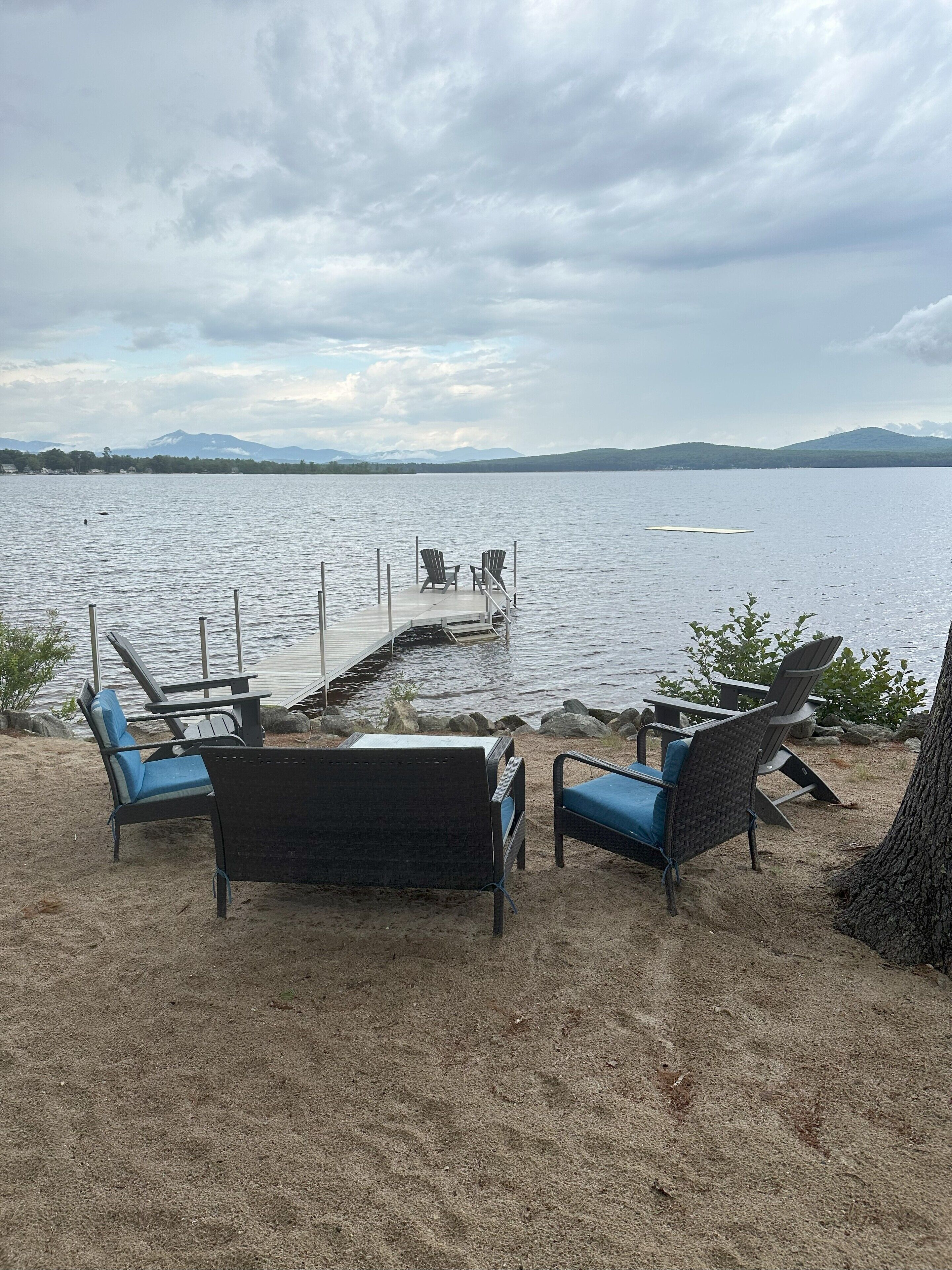A lakeside seating area with chairs and a dock extending into the water.